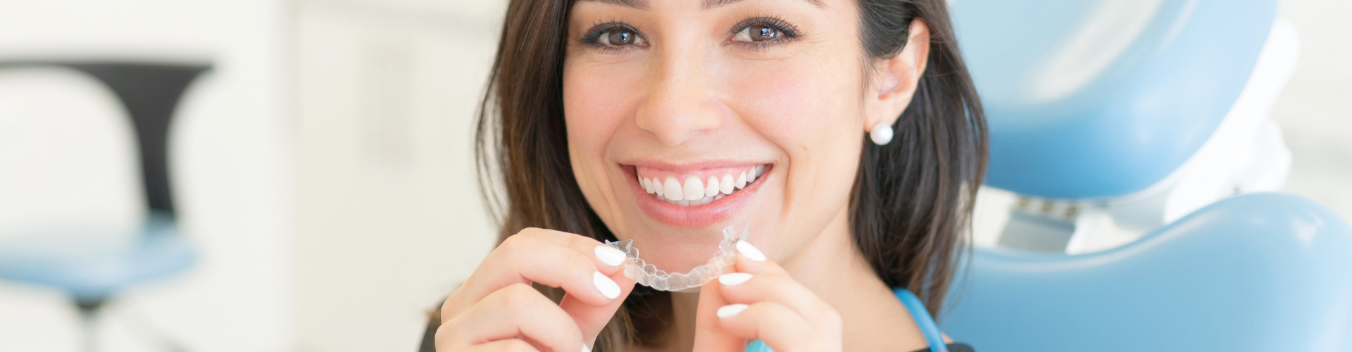 Woman placing clear aligner onto upper teeth.